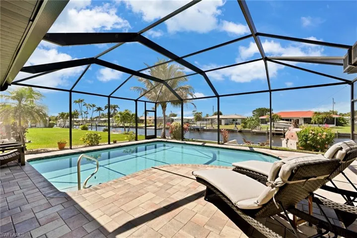 Outdoor heated pool with screen enclosure, a patio, and a water view