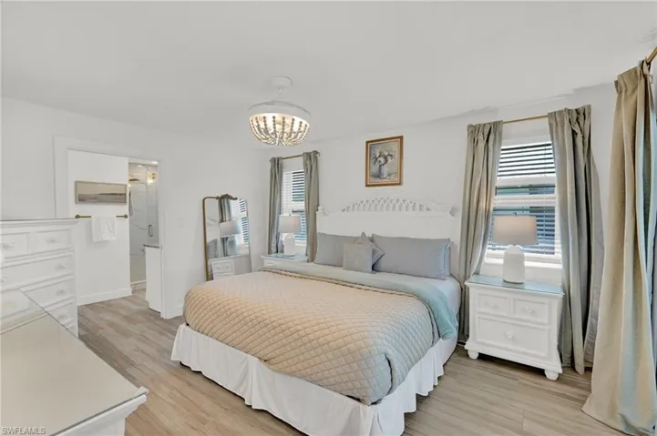 Bedroom featuring connected bathroom, baseboards, a chandelier, and light wood finished floors, ensuite bath, walk in closet, sliders to the pool area
