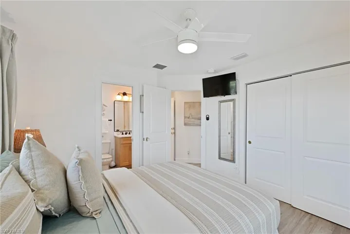 Guest Bedroom featuring visible vents, light wood finished floors, ceiling fan, a closet, and ensuite bathroom and large double closet