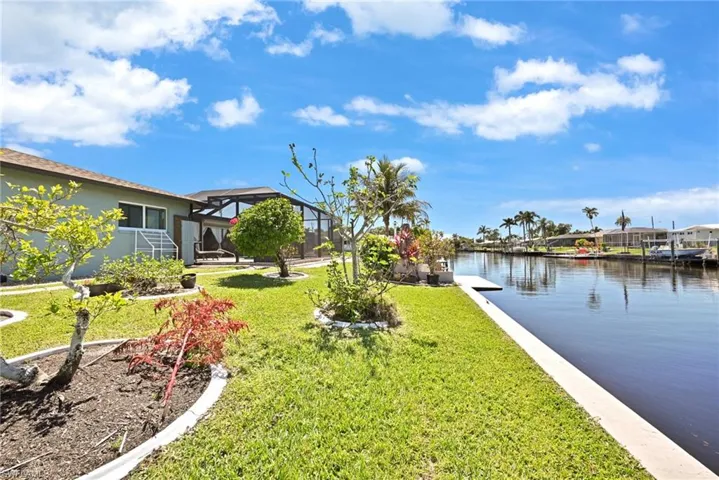 View of yard featuring a lanai, a boat dock, and a water view