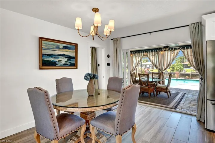 Dining room featuring baseboards, an inviting chandelier, and wood finished floors and pocket sliders to the lanai