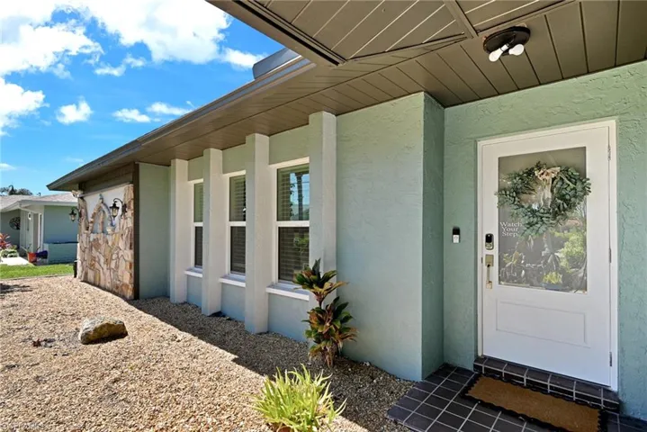 Entrance to property featuring stucco siding, tile  and all impact wind rated windows and doors