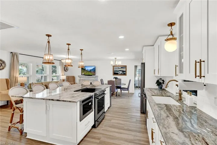 Kitchen with a island bar, appliances with stainless steel finishes, white cabinets, and a farmers sink