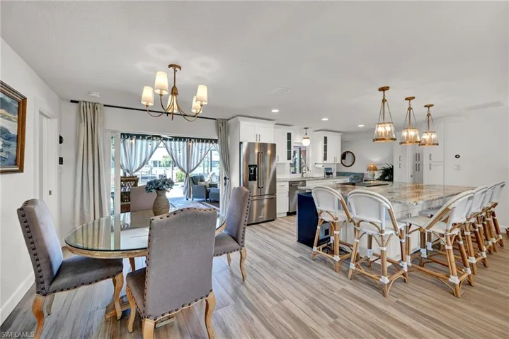 Dining space featuring a notable chandelier, light wood-style floors, recessed lighting, and baseboards and sliders to the lanai