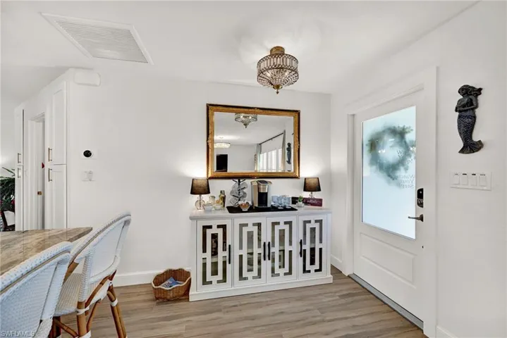 Entrance foyer featuring a notable chandelier, visible vents, light wood-type flooring, and great room with coffee bar