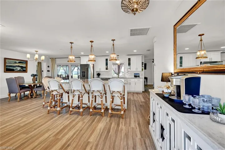 Kitchen featuring an island bar, visible vents, a notable chandelier, high end appliances, and light wood-style flooring