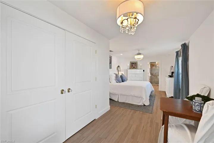 Bedroom featuring an inviting chandelier and light wood-type flooring with huge closet and private entrance to garage and door to side yard.