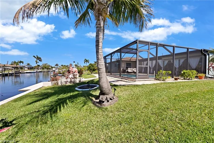 View of yard with an outdoor pool, and a water view and coconut tree