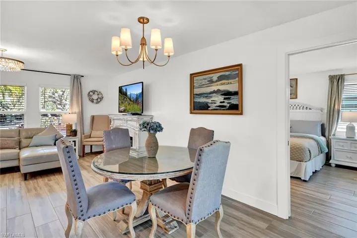 Dining room featuring light wood-style floors, an inviting chandelier, and a healthy amount of sunlight and door to Primary bedroom ensuite