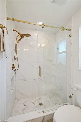 Bathroom with a marble finish shower and toilet