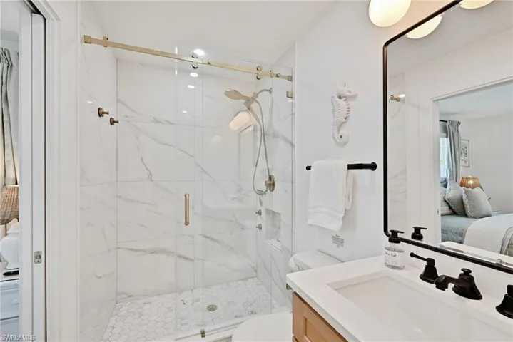 Ensuite bathroom with a marble finish shower, toilet, ensuite bath, and vanity