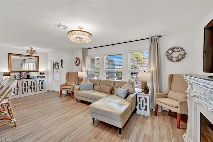 Living area featuring visible vents, light wood-style flooring, and an inviting chandelier and electric fireplace