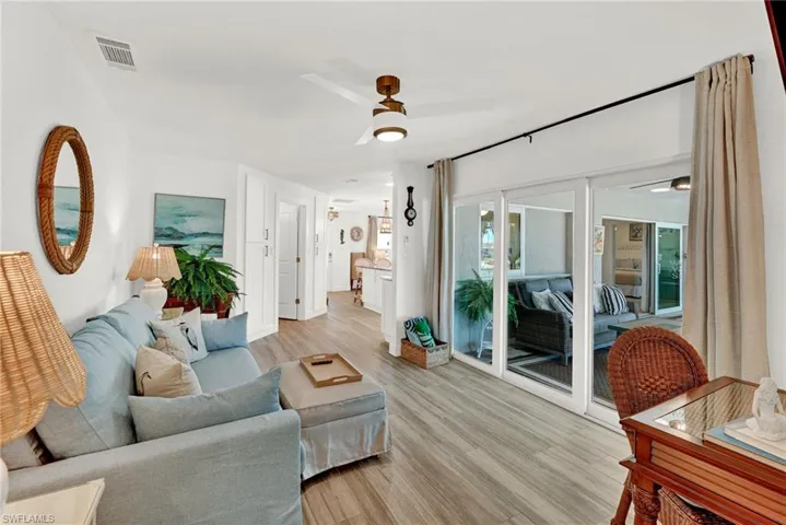 Family room with visible vents, light wood-style flooring, and a ceiling fan and sliders to the pool area