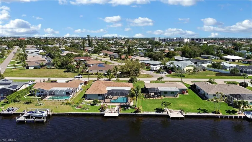 Birds eye view of property featuring a water view with cantilever dock, heated pool, new roof, lemon trees, mango tree, coconut trees and walking distance to Downtown Cape Coral, restaurants and shopping