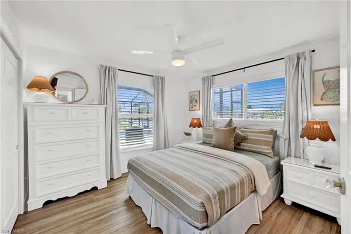 Guest Bedroom number 2 with ensuite bath and view of the pool and canal featuring light wood-style flooring and a ceiling fan