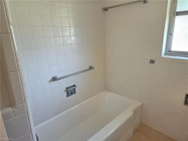 Full bath featuring tile patterned floors, tile walls, and shower / tub combination