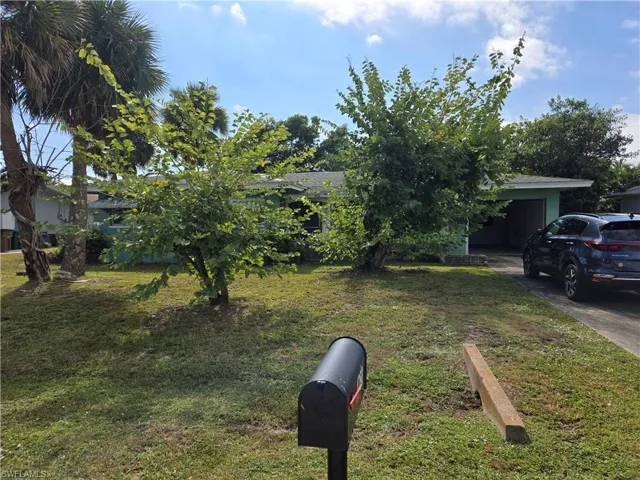 View of grassy yard with concrete driveway and a garage