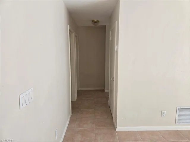 Corridor with baseboards and light tile patterned floors