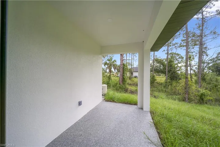 Covered outdoor patio with a textured concrete floor and stucco exterior walls