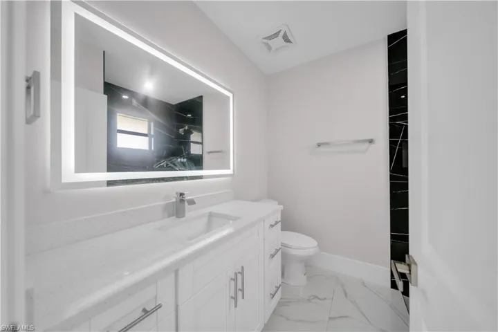 Vanity with a rectangular undermount sink, a chrome single-lever faucet, and a large illuminated mirror