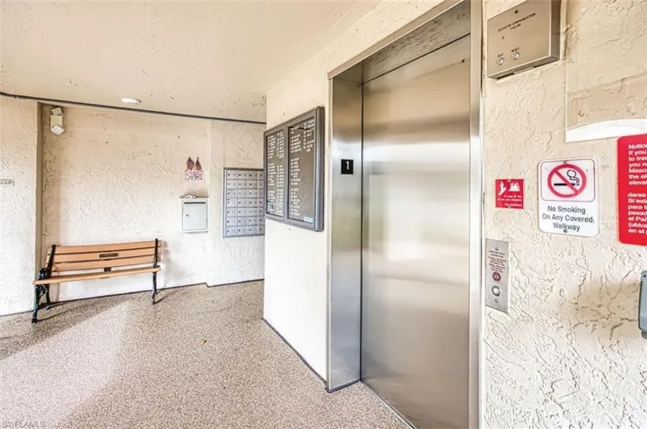 Hall featuring a textured wall, elevator, mail area, a textured ceiling, and speckle patterned floor