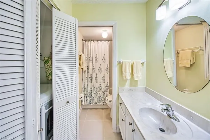 Bathroom with vanity, light tile patterned flooring, a closet, and shower / bath combo with shower curtain