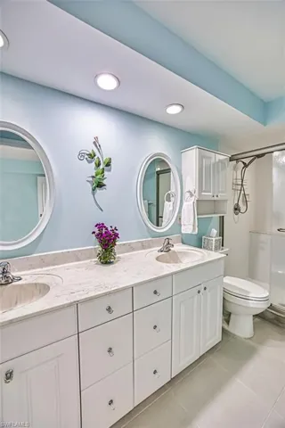 Full bathroom with double vanity, a stall shower, light tile patterned flooring, and recessed lighting