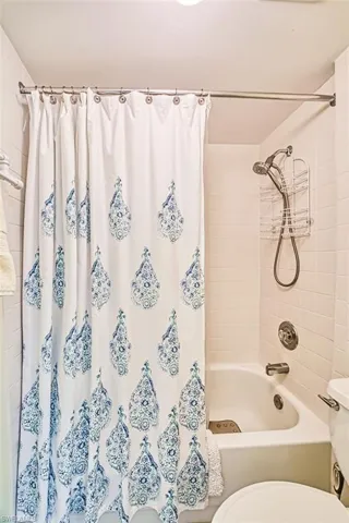Full bathroom featuring toilet and shower / bath combo with shower curtain