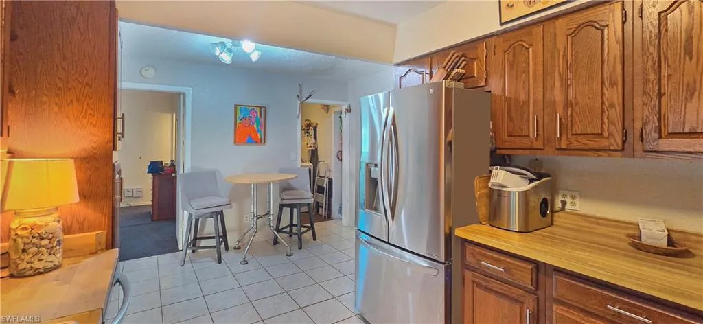 Kitchen featuring wood cabinetry, stainless steel refrigerator, and tiled flooring