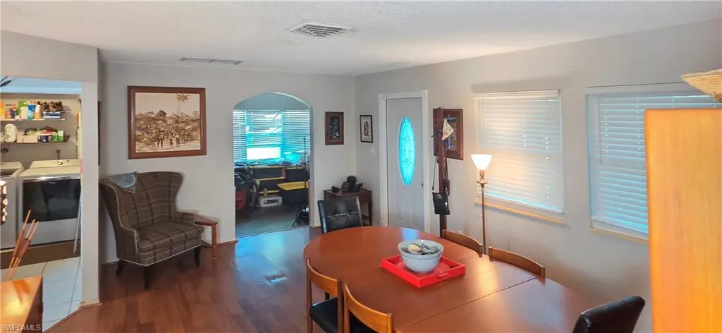 Wood-finish flooring throughout, arched doorway, and multiple windows with blinds
