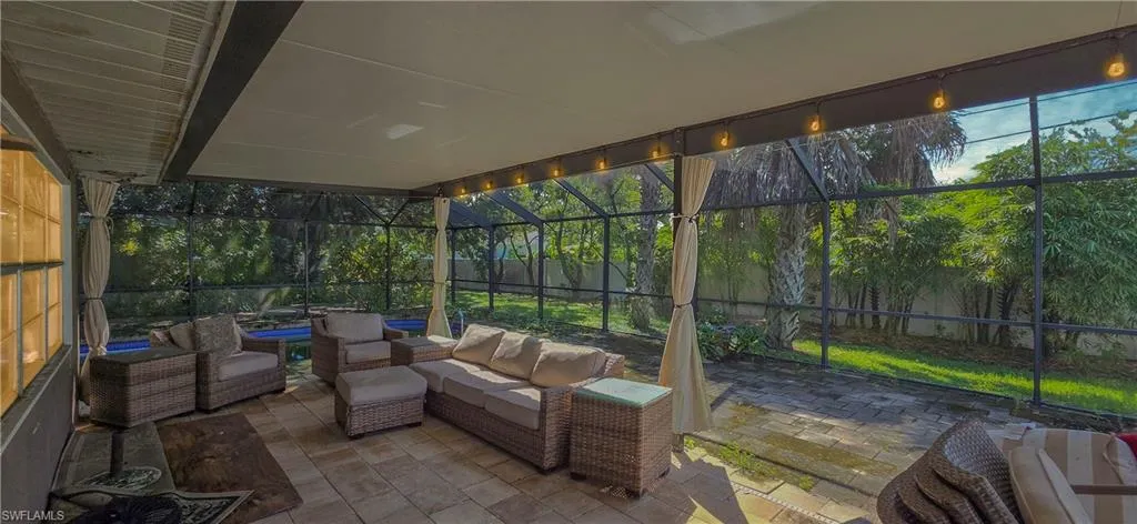 Expansive screened patio featuring a paved floor, a covered ceiling, string lighting, and direct access to the exterior yard