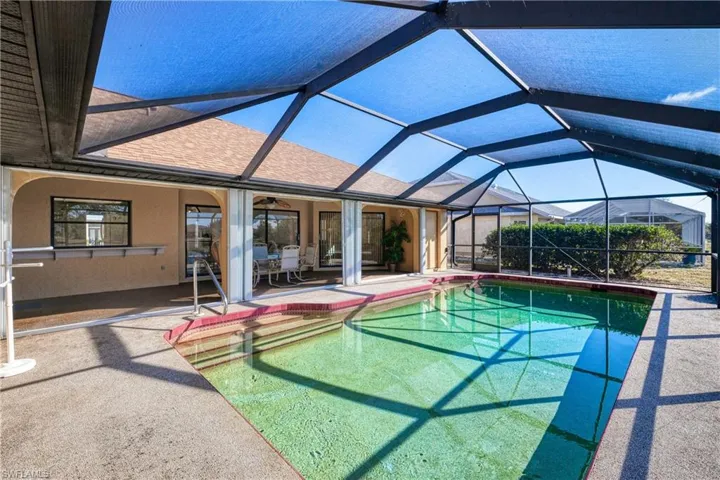View of pool featuring glass enclosure and a patio area