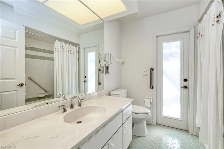 Bathroom featuring tile patterned flooring, vanity, toilet, and a shower with shower curtain