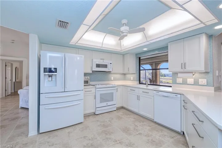 Kitchen with white cabinetry, sink, ceiling fan, white appliances, and decorative backsplash