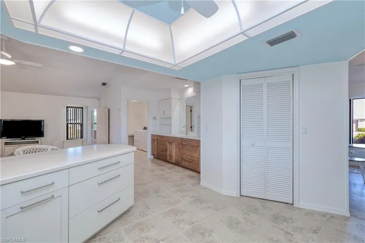 Kitchen with white cabinetry, sink, ceiling fan, lofted ceiling, and washer and dryer