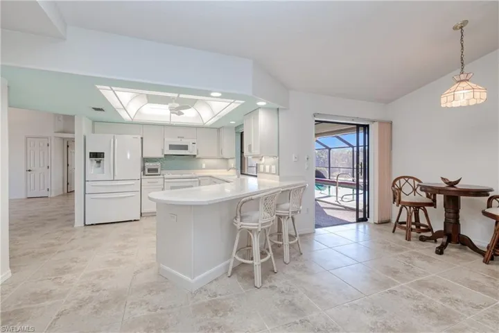 Kitchen featuring white cabinetry, sink, tasteful backsplash, kitchen peninsula, and white appliances