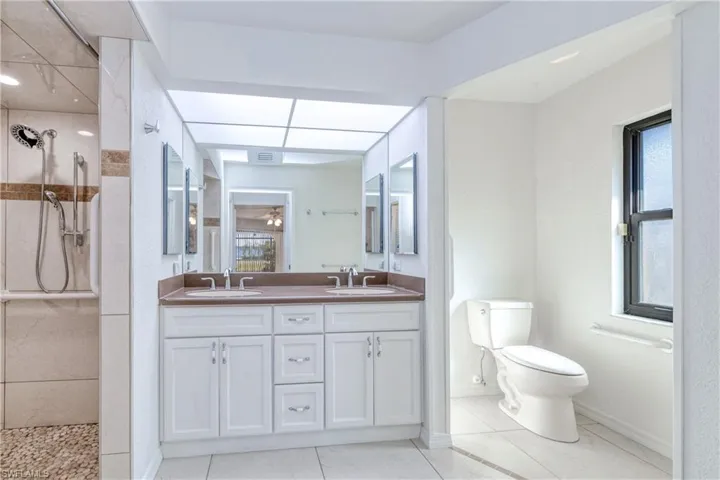 Bathroom with tile patterned floors, toilet, vanity, and tiled shower