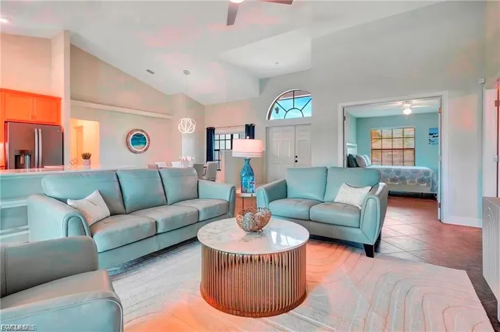 Living area featuring a ceiling fan, light tile patterned floors, and vaulted ceiling