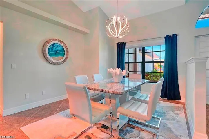 Dining area featuring vaulted ceiling, suspended lighting, and tile patterned flooring