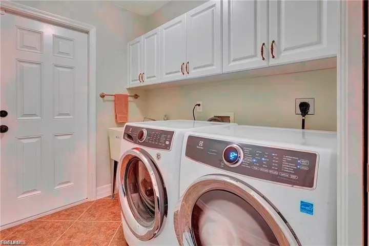 Laundry area with cabinet space, light tile patterned floors, and independent washer and dryer