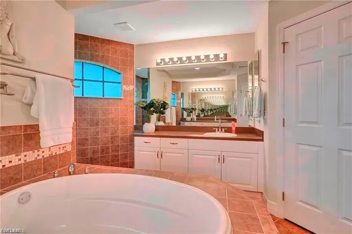 Full bathroom featuring a garden tub, vanity, a walk in shower, and light tile patterned floors