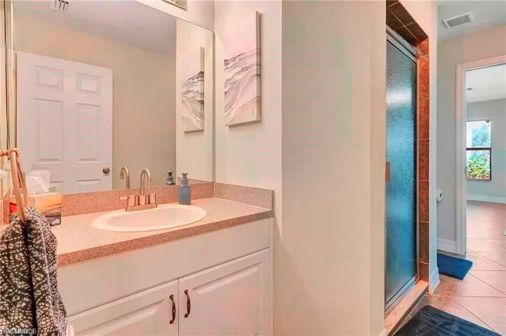Full bath featuring a stall shower, vanity, and tile patterned flooring