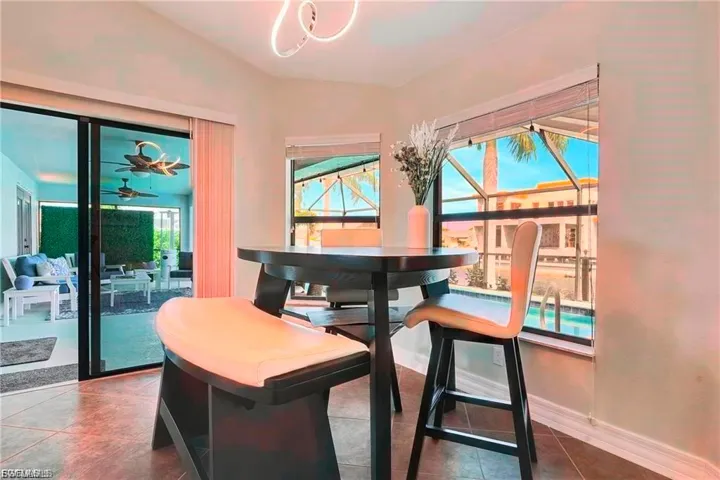 Dining space with a ceiling fan, dark tile patterned floors, and a sunroom