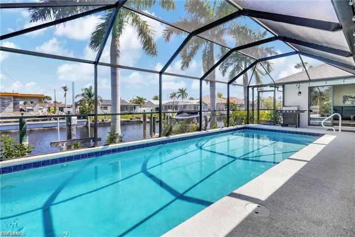 Outdoor pool featuring a residential view, area for grilling, a patio area, a sunroom, and glass enclosure