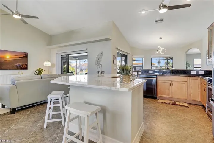 Kitchen with a ceiling fan, a breakfast bar, open floor plan, dishwasher, and lofted ceiling