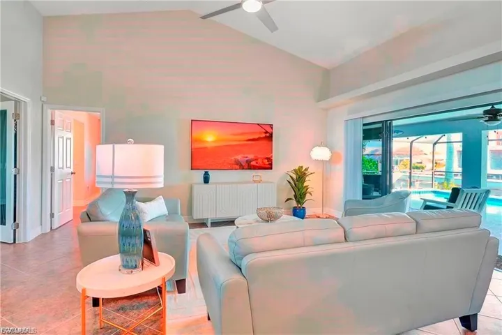Tiled living room with a ceiling fan and lofted ceiling