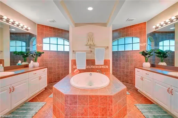 Full bathroom with two vanities, tile walls, a bath, walk in shower, and light tile patterned floors