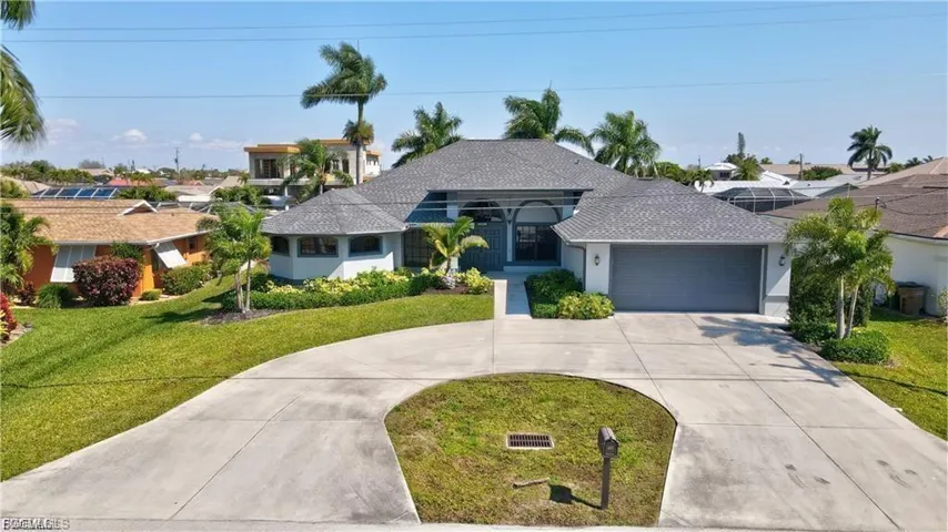 Ranch-style home with curved driveway, a garage, a front yard, stucco siding, and a shingled roof