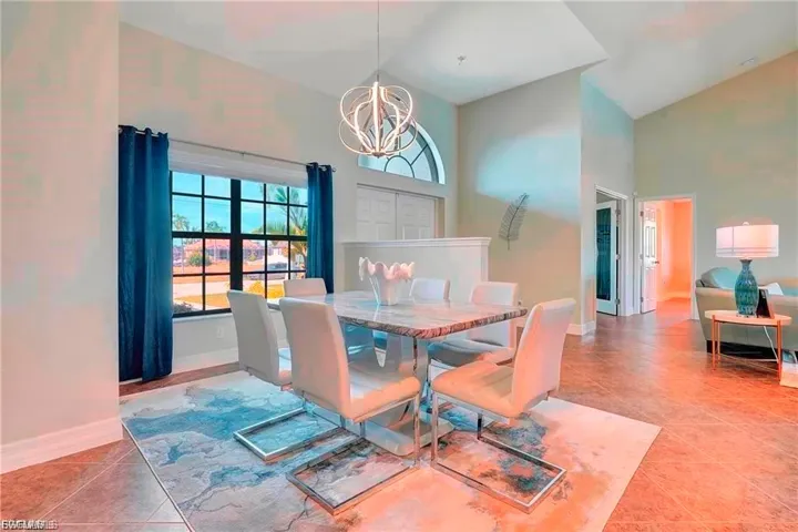 Dining area featuring suspended lighting, lofted ceiling, and light tile patterned floors