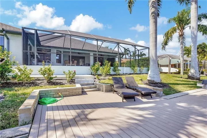 Wooden deck featuring glass enclosure, a sunroom, and a yard